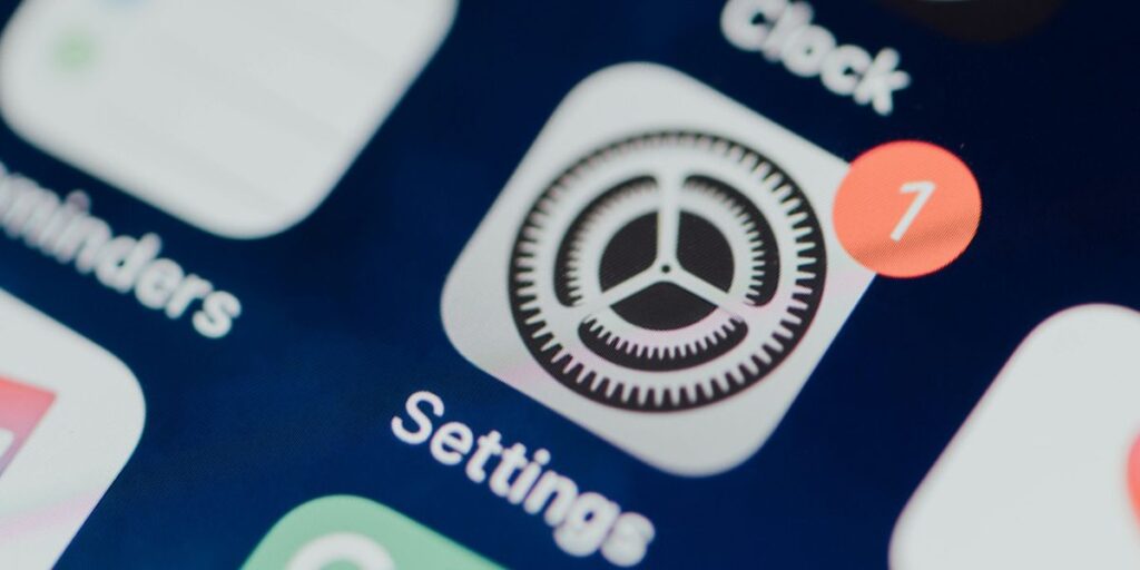 A close-up of an iPhone screen showing the Settings app icon with a red notification badge featuring the number one